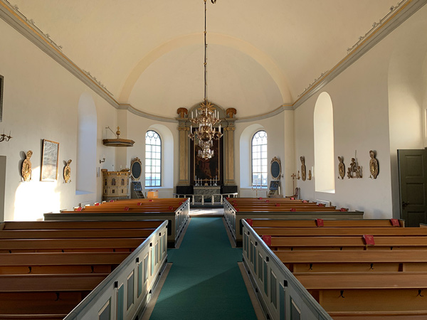 Interiör i en kyrka i Konungsund med bänkar, gången och altaret.