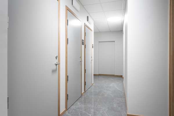 En korridor i Mjölnaren Strömmen Vårdcentral med grått golv och väggar, modernt.