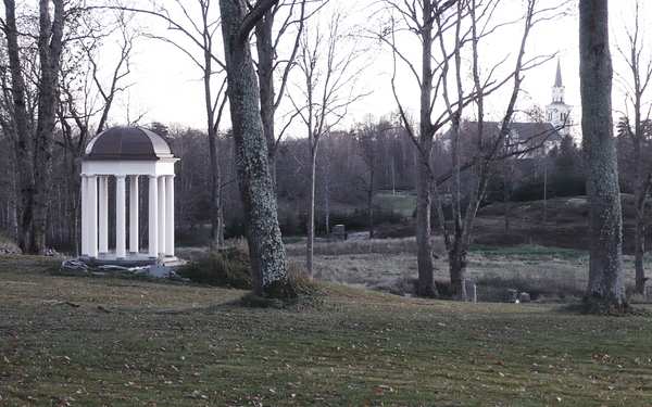 En trädgård i med träd och en vit paviljong på Stjärnvik säteri.
