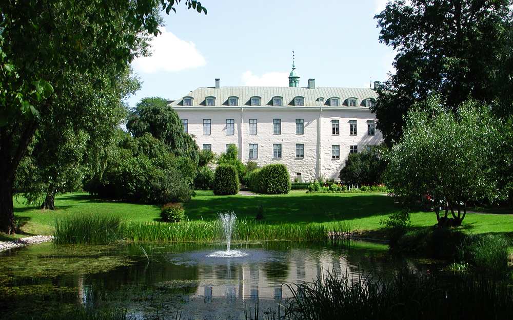 Linköpings slott i grönska med en fontän på gården.