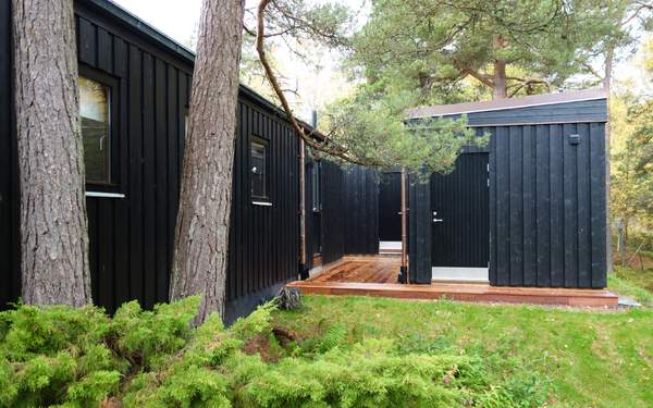 Ett svart trähus i Arkösund med svart dörr och ett trädäck runtom.