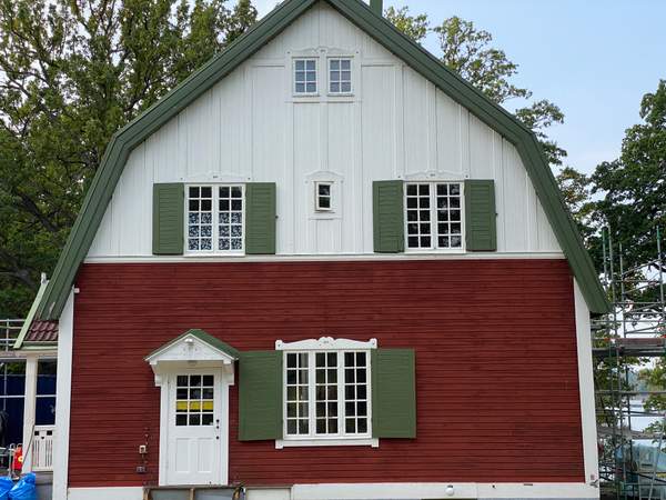 Ett gammal rött trähus i Brokind med vita och gröna detaljer.