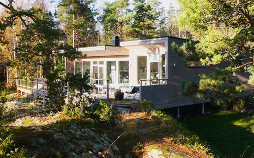 Modernt hus i skärgården med stor veranda och glaspartier som gör att de får en härlig utsikt.