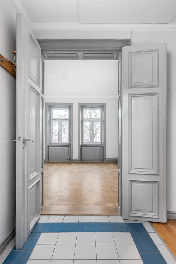 En vit dörr in mot ett rum med trägolv.