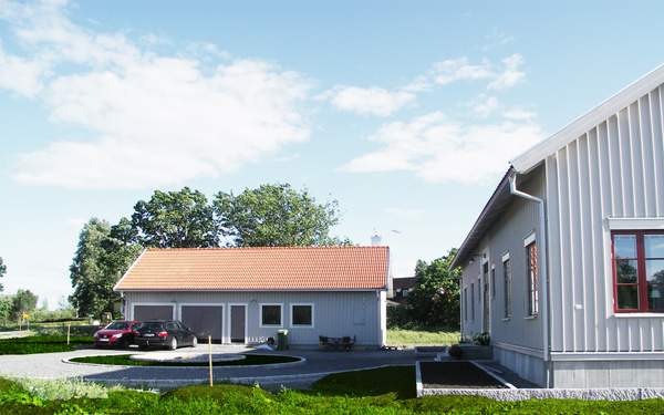 Baksidan av hus i Lindköping, med trädgård, gräsmatta och en plantering.