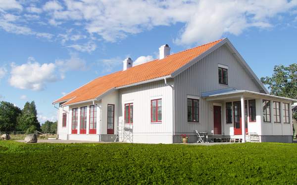 Ett vitt trähus i Lindköping med orange tak och röda detaljer på fönster.