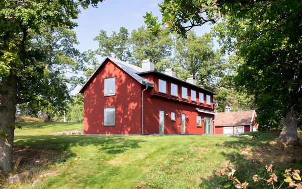 Rött trähus bland grönska.