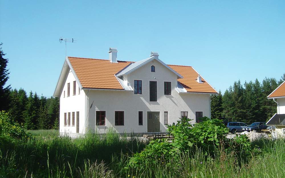 En vit stenvilla med orange tak på landet.