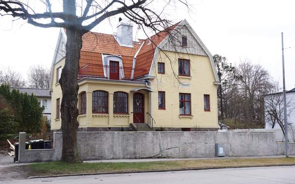 En gul villa i Tapiren 2 med röda fönster, trappa till entrén och orange tak.