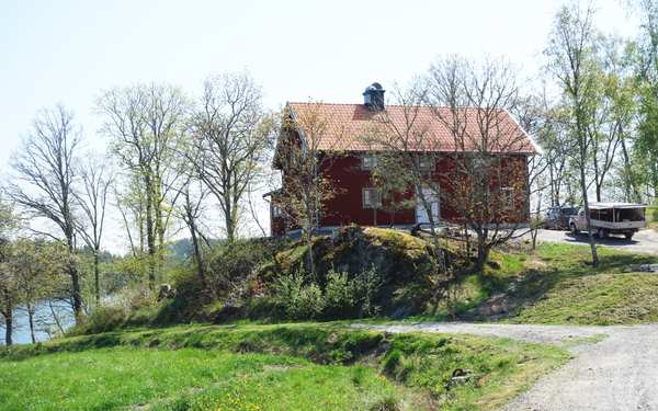 Äldre rött hus i Valdemarsvik med stor tomt vid vattnet.