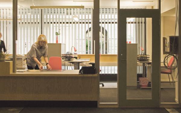 En person som fixar i ordning något bakom receptionen till Kommunhuset Rosen.