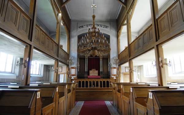 Gången i synagoga i Norrköping med röd matta och bänkar i trä.