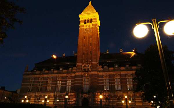 Stort byggnad med torn, i mörker, upplyst av lampor i Norrköpings rådhus