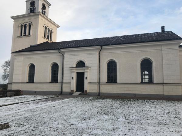 Å Kyrka med svart tak, snö framför.