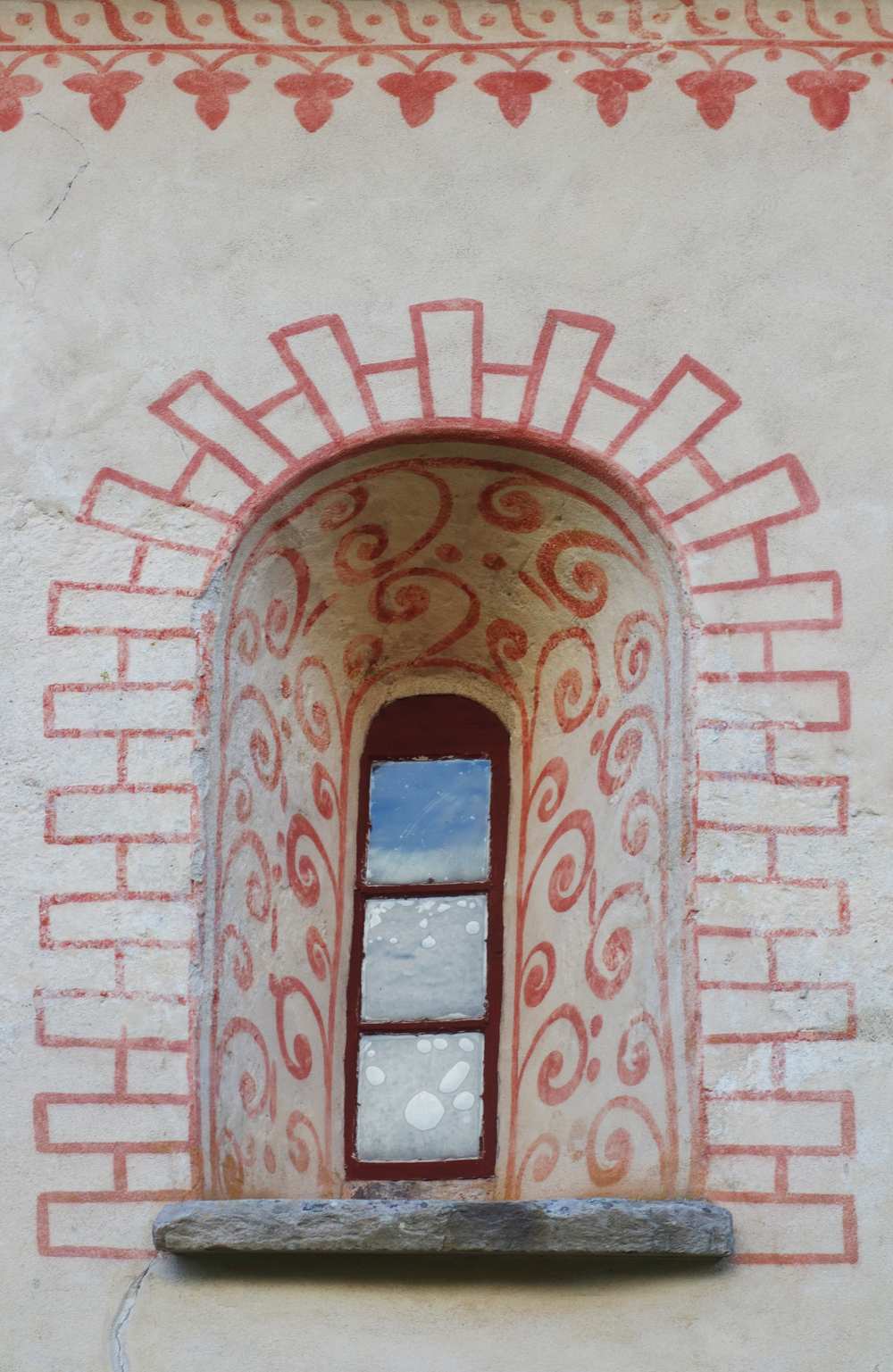Rundat fönster på Dädesjö gamla kyrka med röda detaljer runtomkring