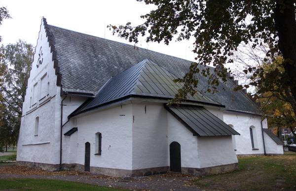 Drothems kyrka med utbyggnad, liten vit del med svart tak.