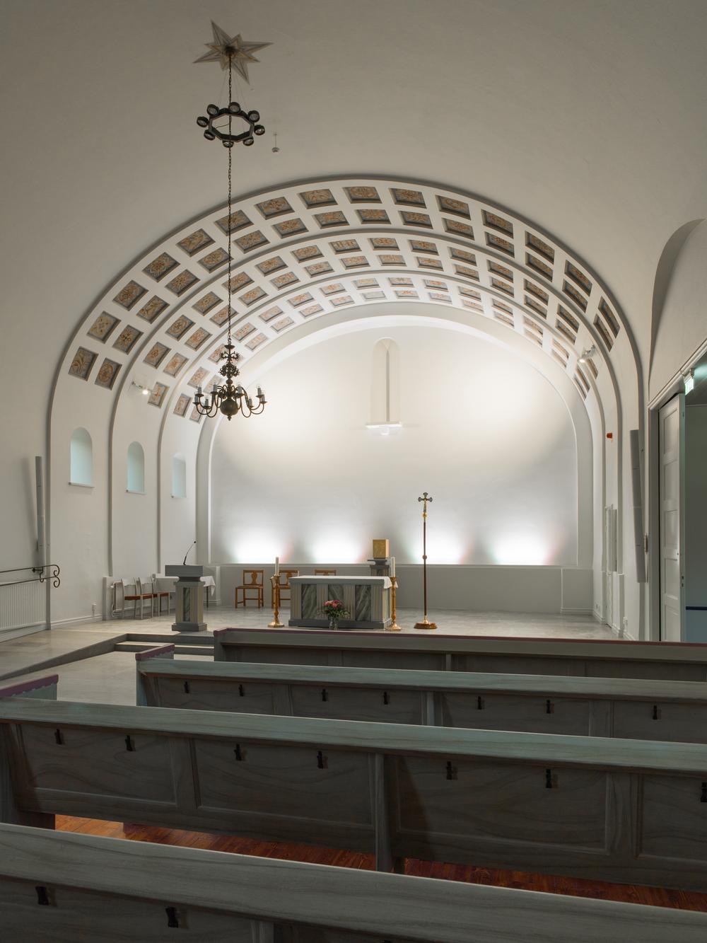 Kyrkoaltaret in Katolska kyrkan i Motala med kupat tak och stolar, ljusstakar.