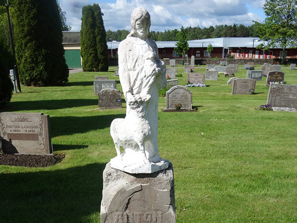En fin gravsten med staty på vid Kumla kyrkogård.