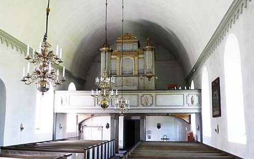 Interiören i Östra Ny kyrka med bänkar, hantverk och orgeln.