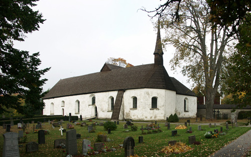 Sankta Maria kyrkogård med en vit och brun kyrka och gravstenar runtomkring.