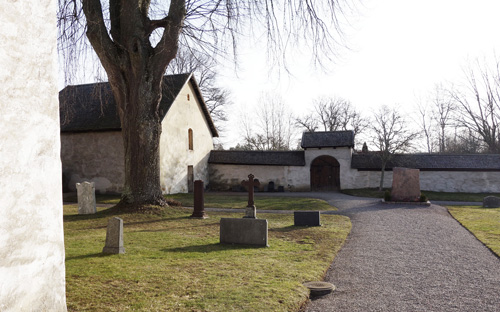 Sankta Maria kyrkogård med en grusväg och ett stort träd.