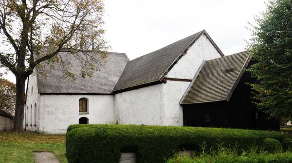 Vit kyrka med ett en trädörr vid Sankta Maria kyrkogård.