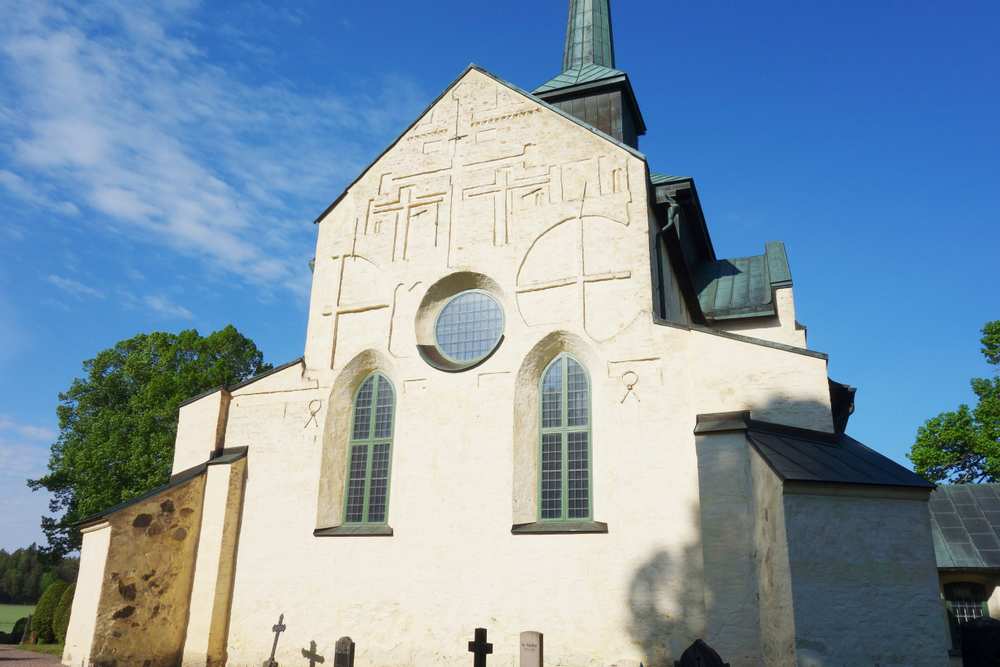Skällviks kyrka i vitt med solen som lyser.