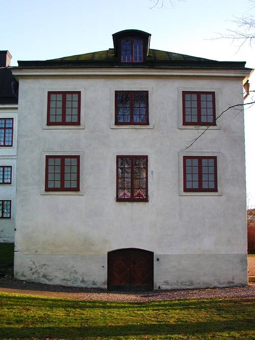 Vit byggnad med röda fönsterkarmar i Vadstena kloster.