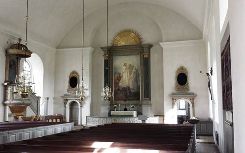 Vy över kyrkosal med bänkar, altaret, tavlor och annat i Vallerstad kyrka.