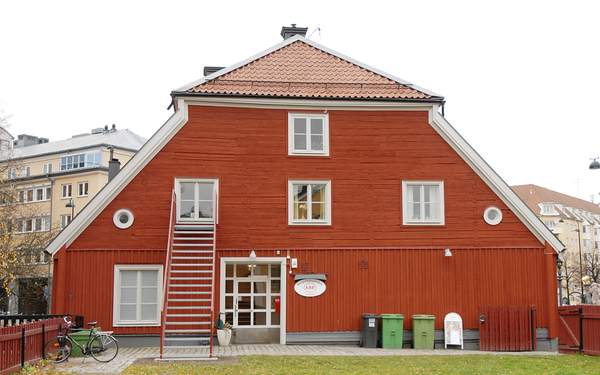 Bergslagsgården med röda och vita detaljer, parkbänkar och lyktstolpar framför.