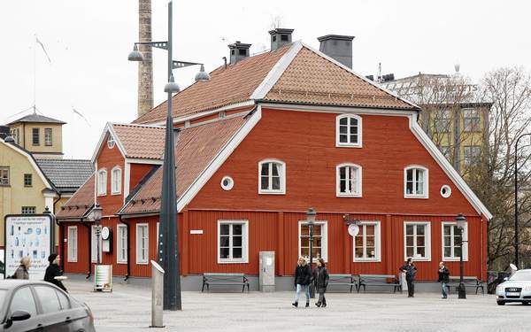 Bergslagsgården med röda och vita detaljer, parkbänkar och lyktstolpar framför.