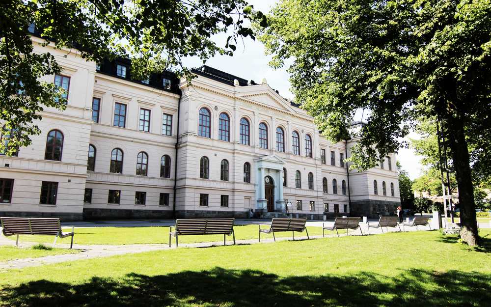 Vit stor byggnad i De Geergymnasiet med flera svarta fönster.