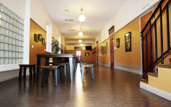 En korridor i De Geergymnasiet med bänkar och bord och gula väggar.