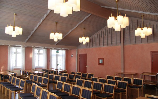 Vacker sal med högt i tak och laxrosa väggar och massa stolar uppställda mot ett håll i Mariagården.