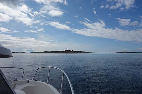 Utsikt från båt mot en ö med Måseskärs fyrplats.