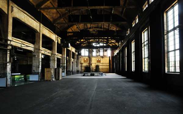 Ett stort långt tomt rum med flera fönster i Gamla Motala verkstad.