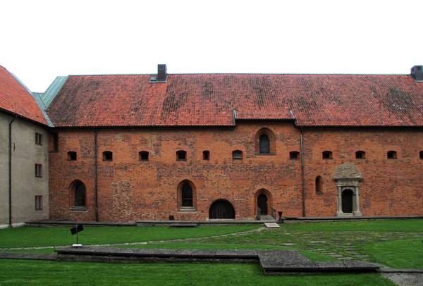 En stor klosterbyggnad i brunorange tegel i Vadstena.