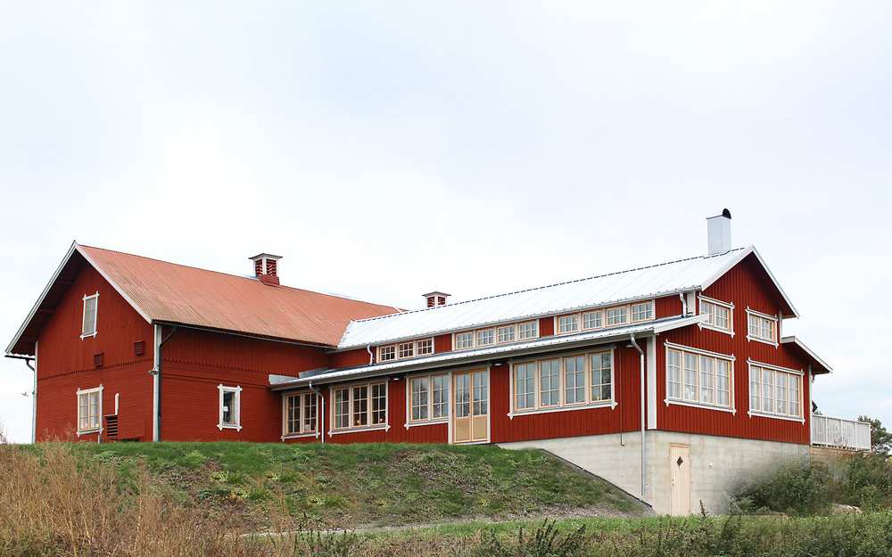 Vänneberga gård, ett rött stort hus med många fönster uppe på en kulle.