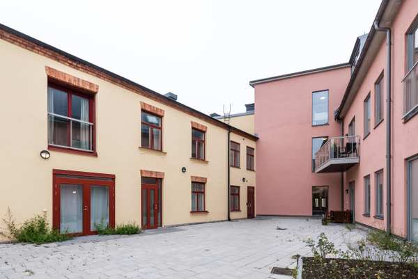 Mjölnaren Strömmen Vårdcentrals byggnad med röda detaljer intill en rosa byggnad.