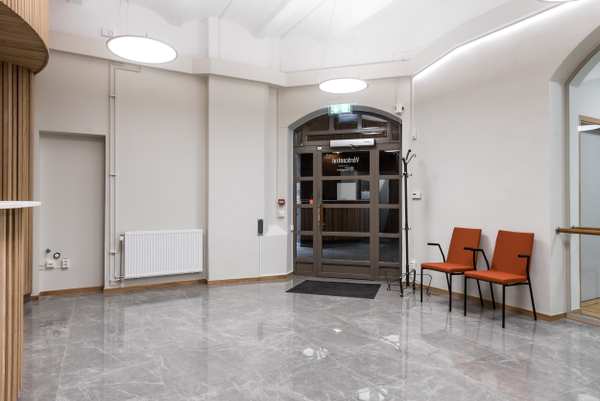 Mjölnaren Strömmen Vårdcentrals vänterum med grått golv och orange stolar.