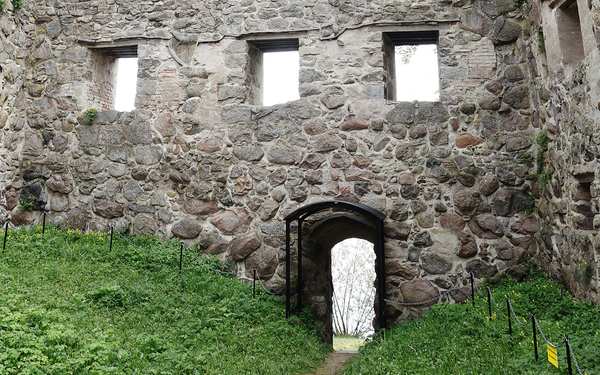 Ingång till Bergkvara ruin med grönska omkring