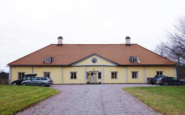 Knuten på en gul villa i Ånhammar med ett vattendrag i bakgrunden.