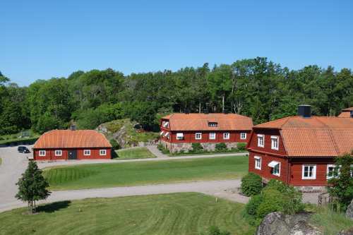 Tre röda hus i Björkviks herrgård med orange tak.