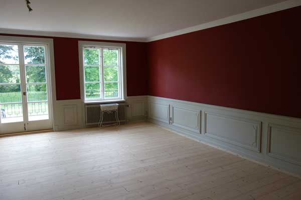 Ett rum med stukaturer och en röd vägg vid Gerstaberg´.