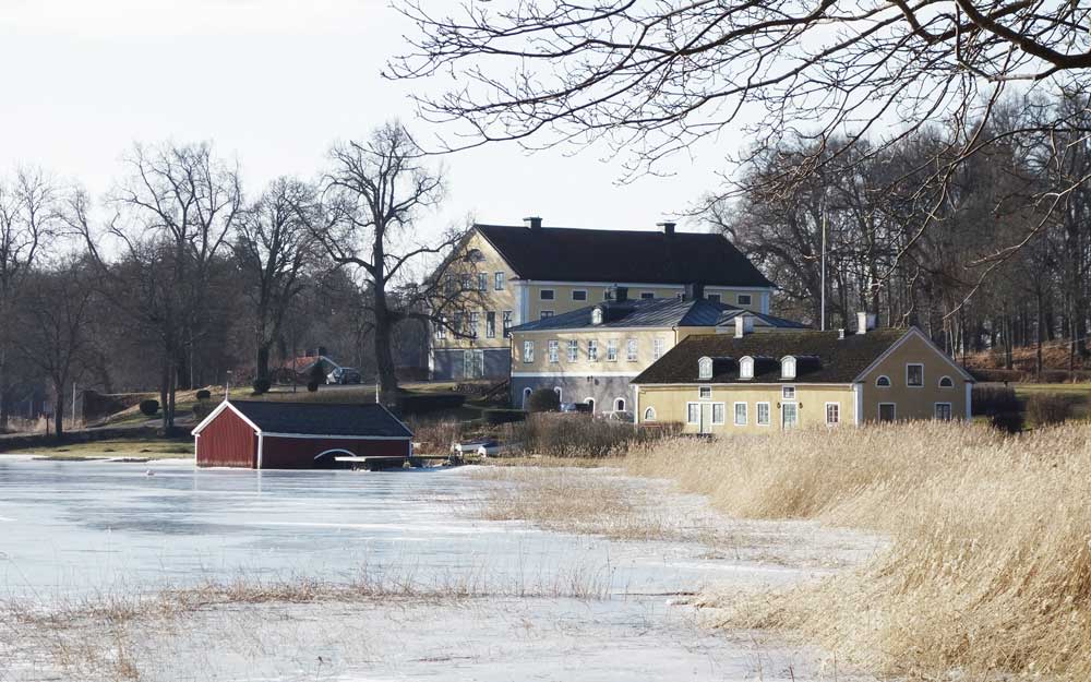 Vacker miljö av herrgård i Kåreholm vid vattnet.