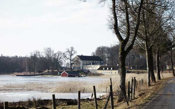 Vacker miljö av herrgård i kåreholm vid vattnet.