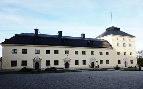 Vit byggnad vid Löfstad slott med svart tak