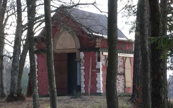 En röd liten kyrka i skog på Rydboholm.