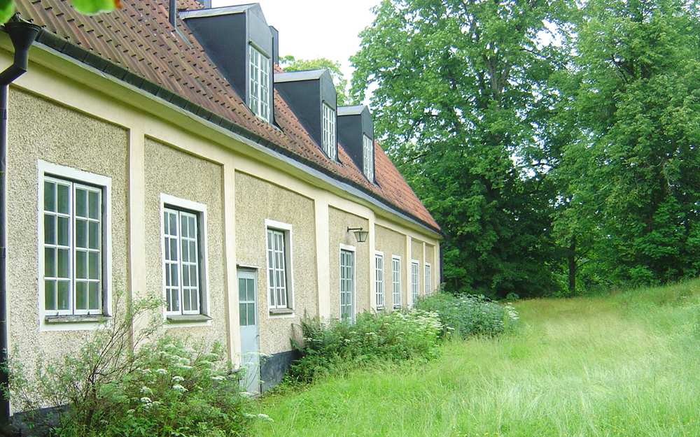 Sidan av ett tegelhus omgiven av grönska vid Skörtinge.