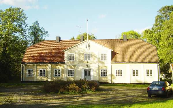 Gult trähus i Skörtinge med massa grönska runtom. 